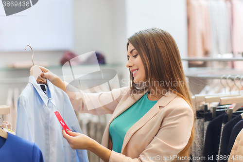 Image of happy young woman choosing clothes in mall