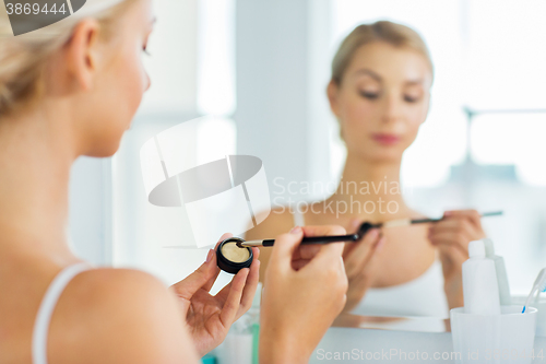 Image of woman with makeup brush and eyeshade at bathroom