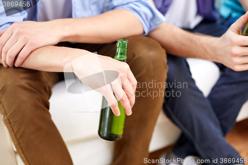 Image of close up of male friends drinking beer at home