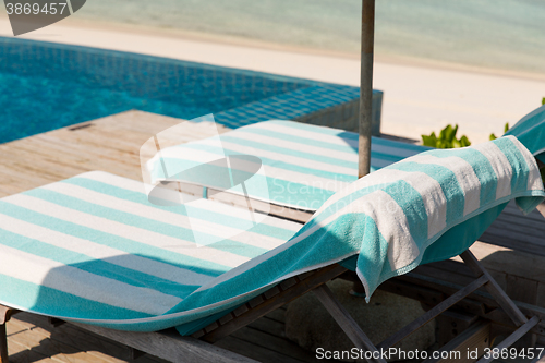 Image of parasol and sunbeds by sea on maldives beach