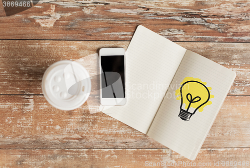 Image of close up of notebook, coffee cup and smartphone