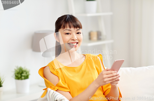 Image of happy asian woman with smartphone at home