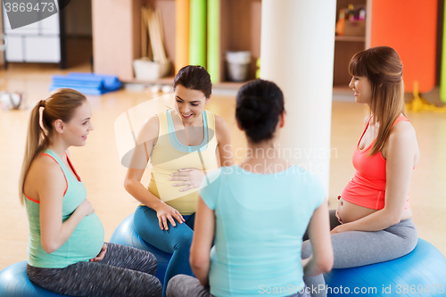 Image of happy pregnant women sitting on balls in gym