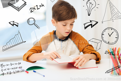 Image of student boy reading book or textbook at home