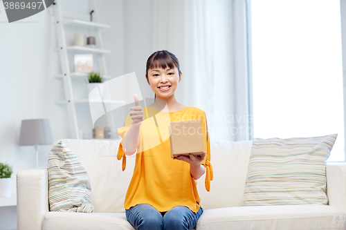 Image of happy asian young woman with parcel box at home