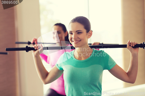 Image of group of people exercising with bars in gym