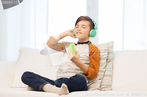 Image of happy boy with smartphone and headphones at home