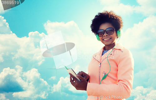 Image of happy young woman with smartphone and headphones