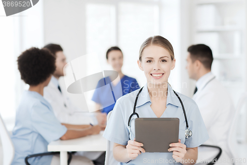 Image of happy doctor with tablet pc over team at clinic