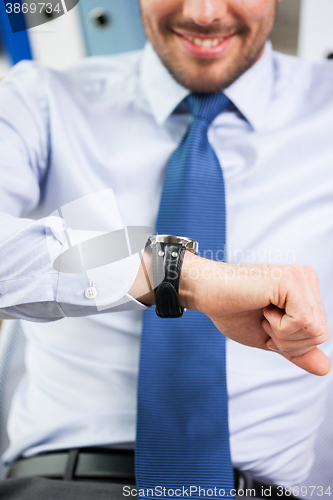 Image of close up of businessman looking at watch in office