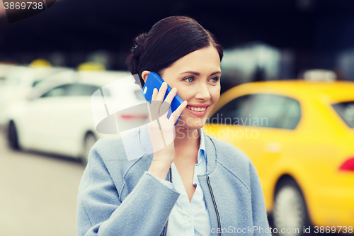 Image of smiling woman with smartphone over taxi in city