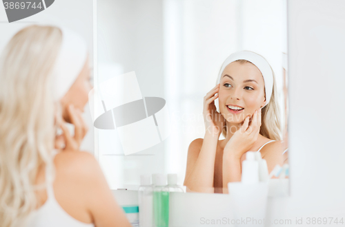 Image of woman in hairband touching her face at bathroom