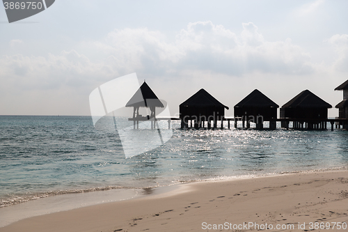 Image of bungalow huts in sea water on exotic resort beach