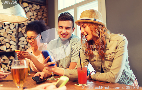 Image of happy friends with smartphones and drinks at bar