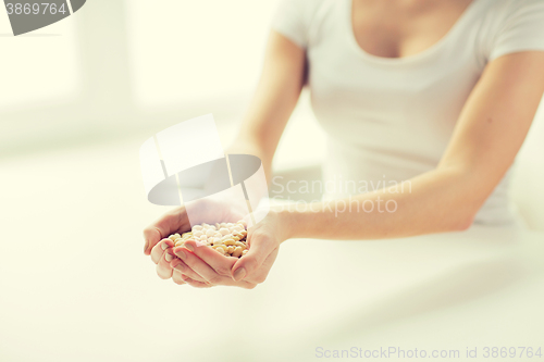 Image of close up of woman hands holding peeled peanuts