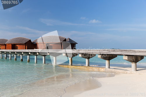 Image of bungalow huts in sea water on exotic resort beach