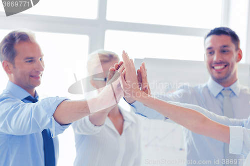 Image of happy business team giving high five in office