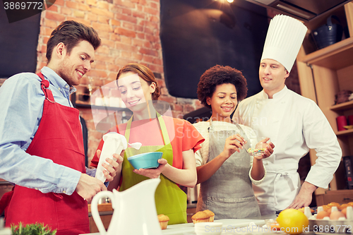 Image of happy friends and chef cook baking in kitchen