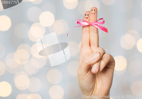 Image of close up of two fingers tied by pink bow knot