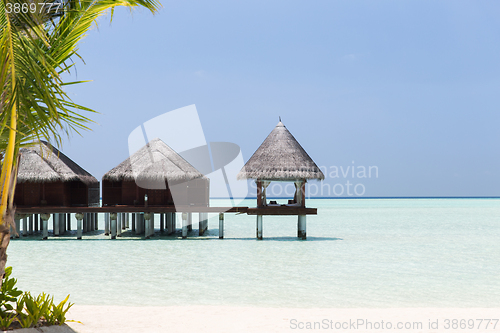 Image of bungalow huts in sea water on exotic resort beach