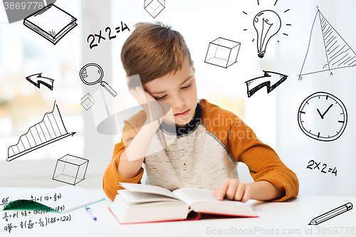 Image of student boy reading book or textbook at home