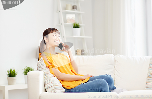 Image of happy asian woman calling on smartphone at home