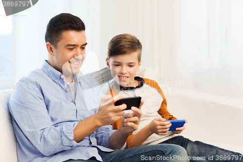 Image of happy father and son with smartphones at home
