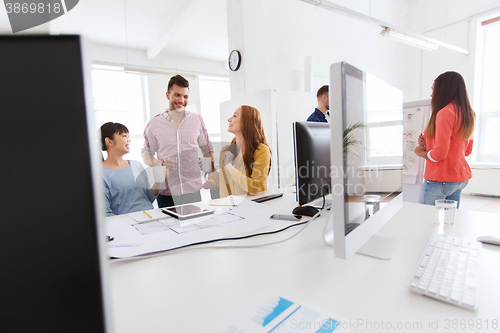 Image of happy creative team rinking coffee at office