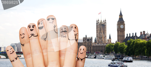 Image of close up of fingers with smiley faces over london