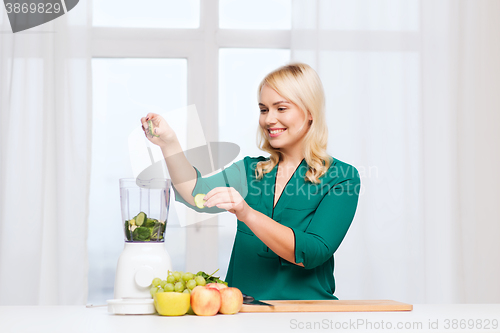 Image of smiling woman with blender cooking food at home