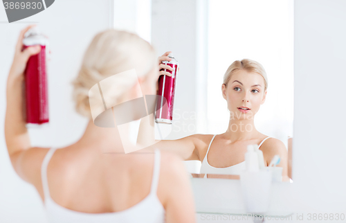 Image of woman with hairspray styling her hair at bathroom