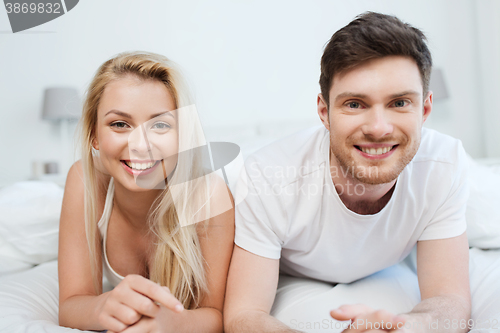 Image of happy couple lying in bed at home