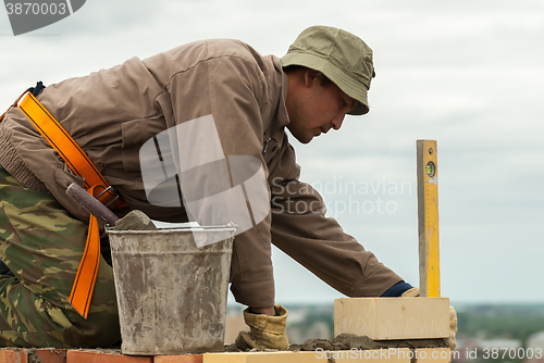 Image of Bricklayer works on high house construction