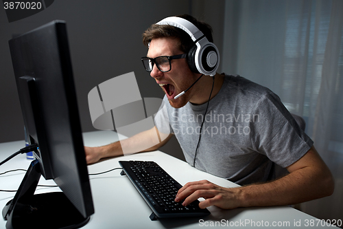 Image of man in headset playing computer video game at home