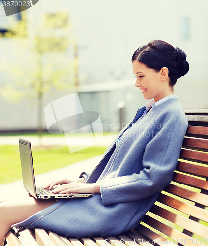 Image of smiling business woman with laptop in city