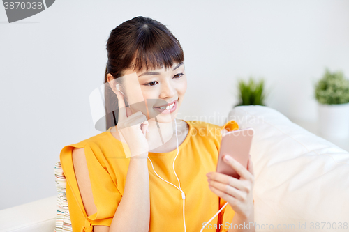 Image of happy asian woman with smartphone and earphones