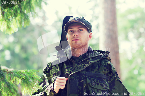 Image of young soldier or hunter with gun in forest