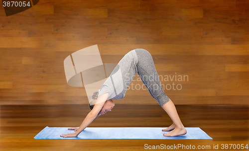 Image of woman making yoga dog pose on mat