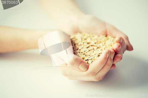 Image of close up of woman hands holding oatmeal flakes