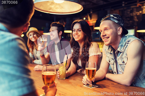 Image of happy friends with drinks talking at bar or pub