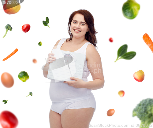 Image of happy young plus size woman holding scales