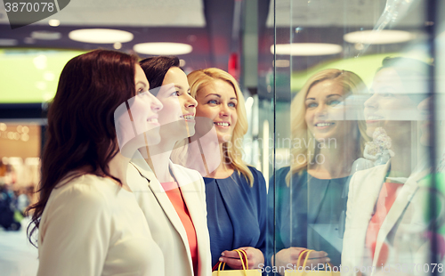 Image of happy women looking at jewelry shop window in mall