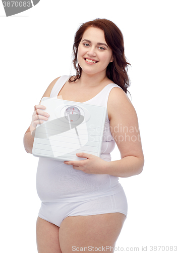 Image of happy young plus size woman holding scales