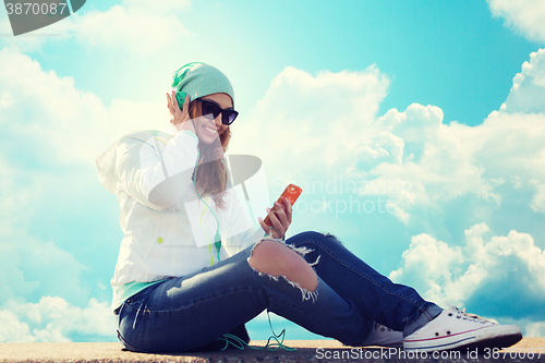 Image of happy young woman with smartphone and headphones