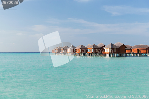 Image of bungalow huts in sea water on exotic resort beach