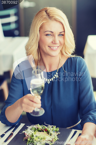 Image of happy woman drinking champagne at restaurant