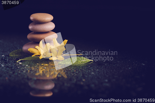 Image of balancing zen stones on black with yellow flower