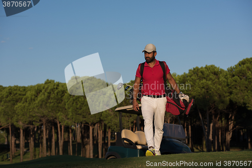 Image of golfer  walking and carrying golf  bag