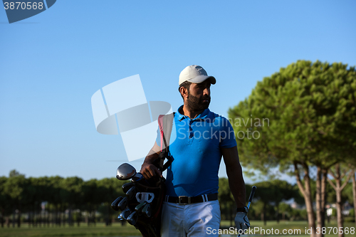 Image of golfer  walking and carrying bag