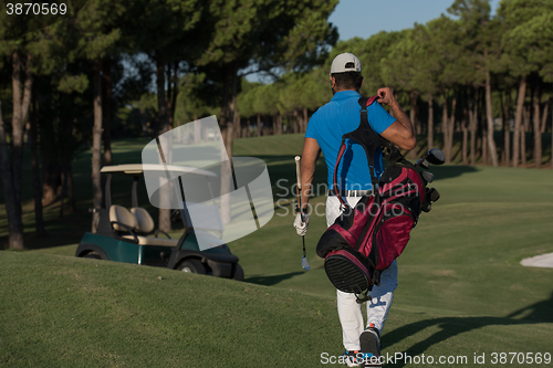 Image of golfer  walking and carrying golf  bag